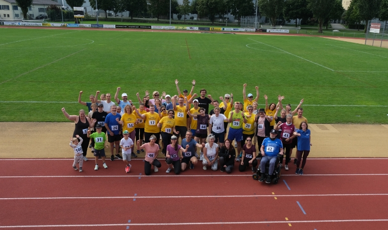 Gruppenfoto der Teilnehmenden des FRAGILE-Spendenlaufs. Die Menschen lachen und strecken die Hände in die Höhe.